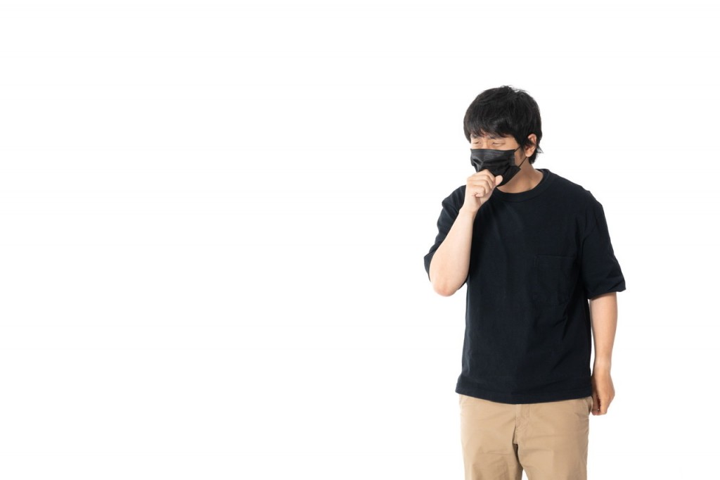 マスクをして咳をしている人の画像